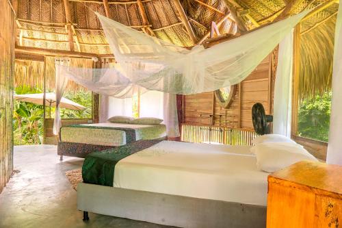 two beds in a room with a hammock at Magic Green Dentro del Parque Tayrona in El Zaino