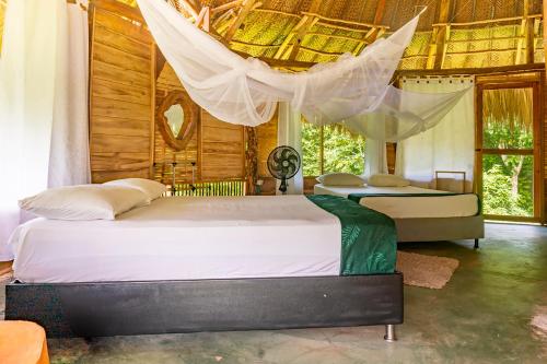 a bedroom with two beds and a net at Magic Green Dentro del Parque Tayrona in El Zaino