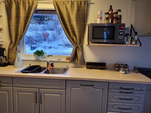 a kitchen with a sink and a microwave and a window at Stort privat rom in Hauknes