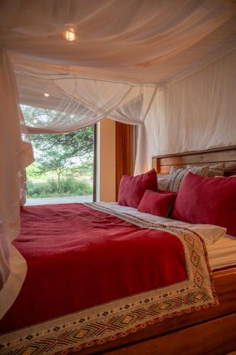 a bedroom with a large red bed with a window at Lodge du Ranch de Bandia in Sindia