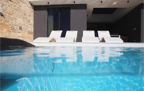 a group of white chairs sitting next to a swimming pool at Villa K2 in Zadar