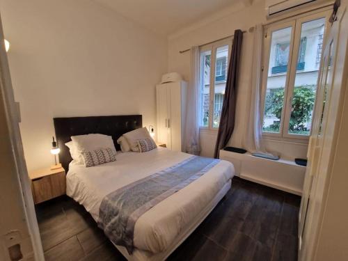 une chambre avec un grand lit et deux fenêtres dans l'établissement Appartment 2 pieces hyper centre ville, à Nice