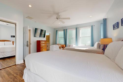a white bedroom with two beds and a television at 126 Grand Pavilion in Isle of Palms
