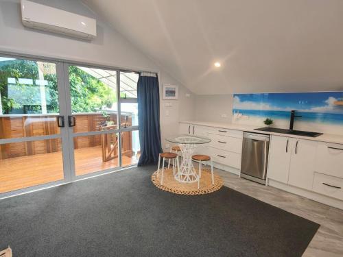 a kitchen with a glass table and a balcony at Welcome to Howick Auckland in Auckland