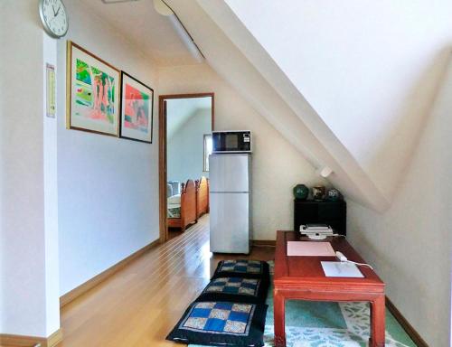 AsahikawaにあるGuest House Ito3F 屋根裏部屋丘の上白亜の洋館風別荘静かな小さなお宿1名から3名のテーブルと冷蔵庫のあるリビングルーム