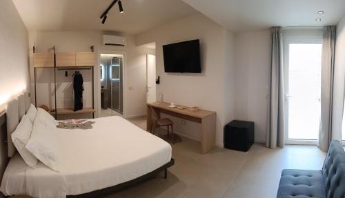 a bedroom with a bed and a desk and a television at Luxury Rooms Marenaria and SPA in Custonaci