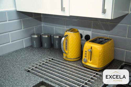 a kitchen counter with a yellow toaster and trash cans at Potter's Cove in Watford - Walk to the Studios in Leavesden Green