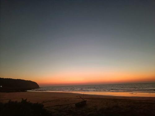 a sunset at the beach with a boat on the beach at Shantadurga Beachside Homestay in Guhagar