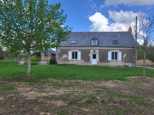 une vieille maison avec un arbre dans la cour dans l'établissement Le domaine de la remangerie, à Nogent-sur-Loir