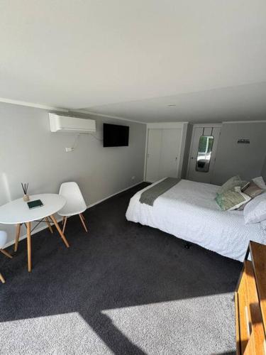 a bedroom with a bed and a table and a tv at The Avenues Hideaway in Tauranga