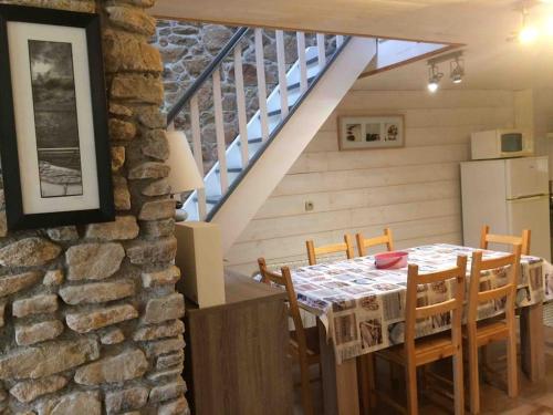 a dining room with a table and a stone wall at Gite bord de mer La Hague Port Racine in Saint-Germain-des-Vaux