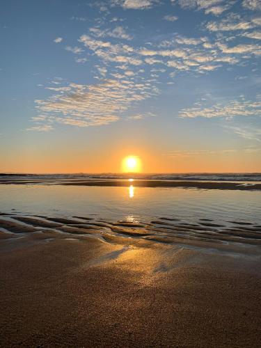 a sunset on a beach with the sun reflecting in the water at 11 Meadow View in Newquay