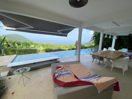 a living room with a table and a swimming pool at REVE BLEU - Villa classée 4* vue mer - 6 pers in Deshaies
