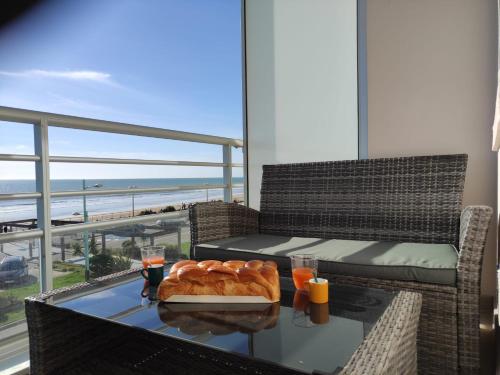 - une table avec un plateau de pain et des boissons sur un balcon dans l'établissement FACE MER grand T3 familial, parking gratuit, à Saint-Jean-de-Monts