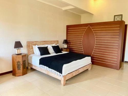 a bedroom with a large bed with a wooden headboard at Pleasant Balinese Style Lotus in Umalas