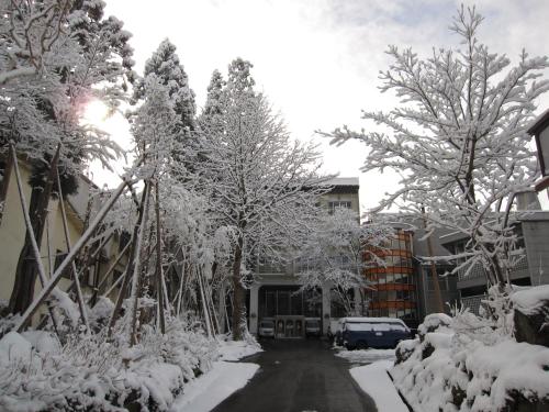 a street covered in snow with trees and buildings at Akakura Hotel in Myoko