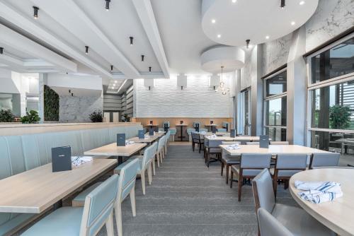 a dining room with tables and chairs and windows at Sandman Signature Toronto Airport Hotel in Toronto