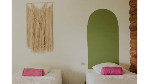 a room with two beds with pink and white pillows at Saasil Retreat in Tzununá
