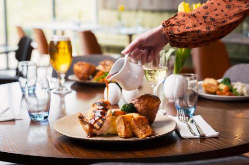 a table with a plate of food and a person reaching for a spoon at voco Winchester Hotel & Spa by IHG in Winchester