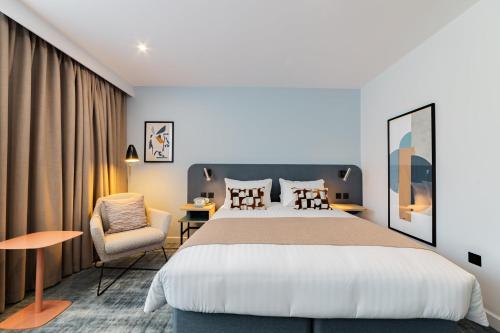 a hotel room with a large bed and a chair at voco Winchester Hotel & Spa by IHG in Winchester