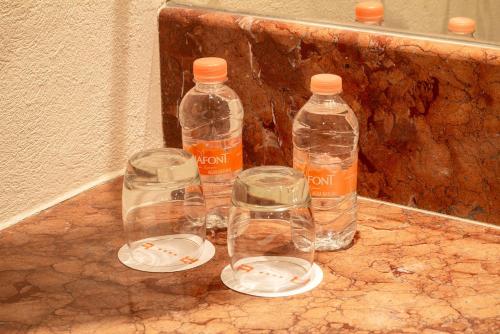 three glass bottles sitting on top of a counter at Real Inn Guadalajara Expo in Guadalajara