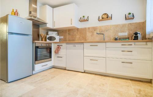  La cuisine est équipée de placards blancs et d'un réfrigérateur. dans l'établissement Ricard, à Arles