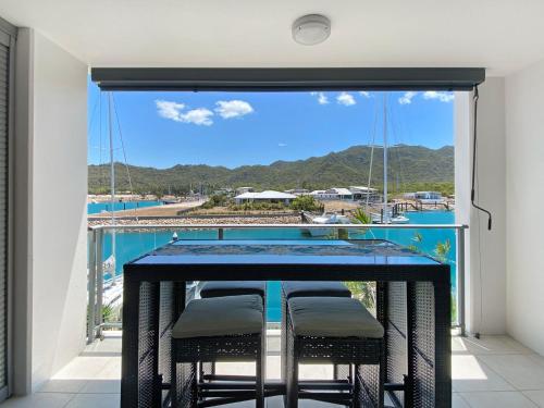 a table with chairs on a balcony with a view at Blue on Blue Superior Studio Room 1221 in Nelly Bay