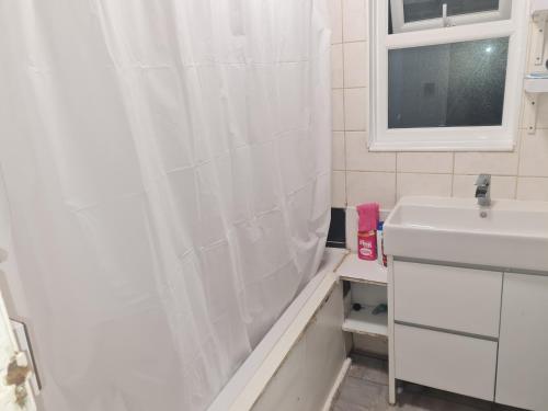 a bathroom with a shower curtain and a sink at Guesthouse in Tilbury