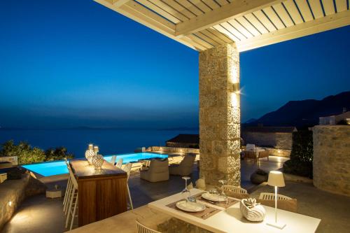a patio with a view of a pool at night at BASSA MAINA Villas & Suites in Areopolis