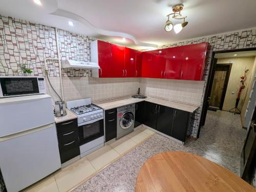a kitchen with red cabinets and a washer and dryer at 1 комнатная квартира in Uralsk