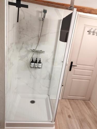 d'une douche avec des murs en marbre blanc et une porte. dans l'établissement Sous les toits de Millau - Appartement cosy et chaleureux, à Millau