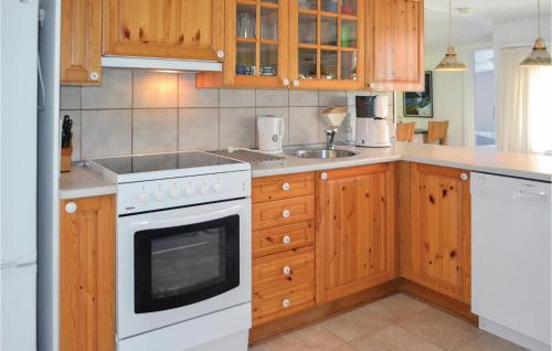 a kitchen with wooden cabinets and a white stove top oven at Holiday Home Sydskrænten Oksbøl in Oksbøl
