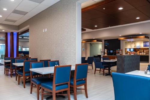 a dining room with tables and blue chairs at Holiday Inn Express & Suites Orlando- Lake Buena Vista by IHG in Orlando