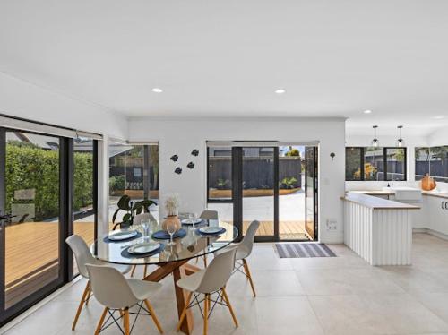 a dining room and kitchen with a table and chairs at Aqua Vista Seaside Retreat in Papamoa