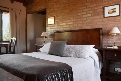 a bedroom with a large bed and a brick wall at Refugio de Luna -Cabañas & Suites- in Nono