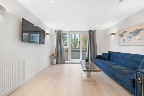 a living room with a blue couch and a tv at Cosy Modern1 Bed Apartment, by Excel London, City Airport & O2 in London