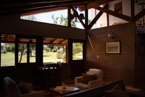 a living room with chairs and tables and windows at Refugio de Luna -Cabañas & Suites- in Nono