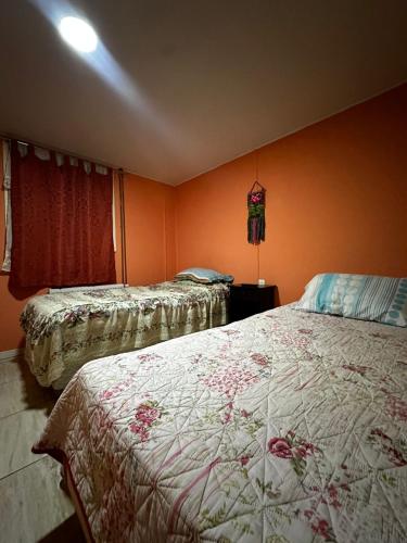 a bedroom with two beds and orange walls at Hostal Vista al Mar in Puerto Natales