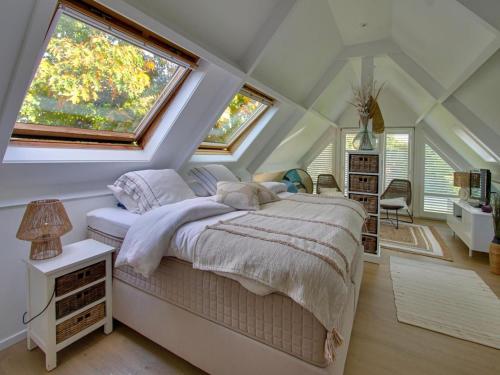 a bedroom with a large bed with two windows at A charming holiday home with a swimming pool in Belleghem