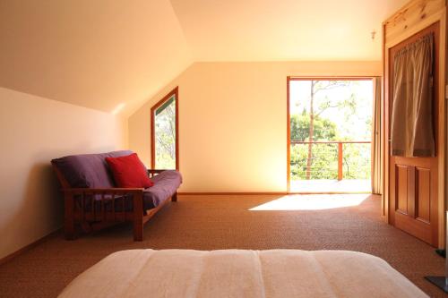 a bedroom with a couch and a large window at Tranquil Point in Cygnet