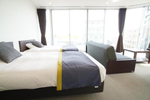 a hotel room with two beds and a chair at 3 Wellness in Okayama