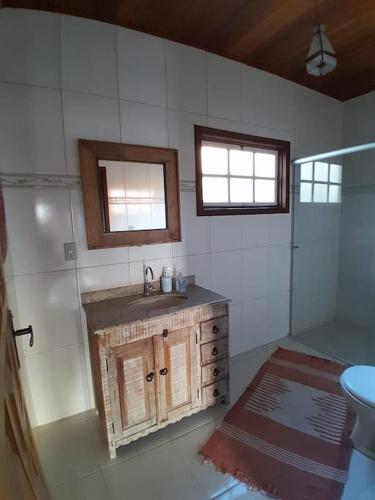 a bathroom with a sink and a toilet and a window at Casa Flamboiam in Tiradentes