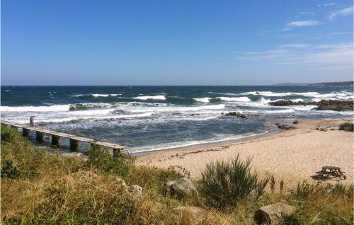 a beach with a pier and waves in the ocean at Lovely Home In Allinge With Wifi in Allinge