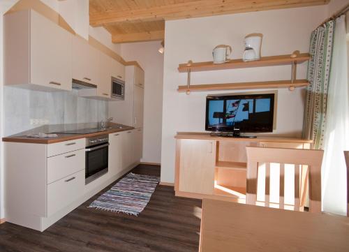 شقة شاوبنشتاينر في زيل أم سي: مطبخ مع دواليب بيضاء وتلفزيون بشاشة مسطحة