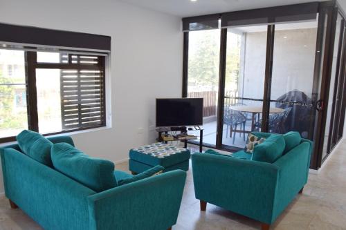 a living room with two blue couches and a tv at Waterford Apartment 5 in South West Rocks