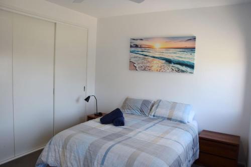 a bedroom with a bed and a painting on the wall at Waterford Apartment 5 in South West Rocks