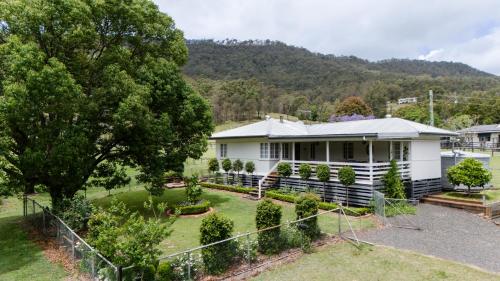 una casa blanca con un jardín delante en Cottage on Lamington, en Canungra