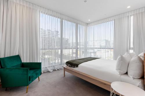 Wynyard Quarter Apartments by Urban Rest في أوكلاند: غرفة نوم بسرير كبير وكرسي أخضر