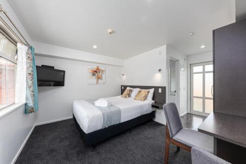 a bedroom with a bed and a tv and a chair at 315 Motel Riccarton in Christchurch
