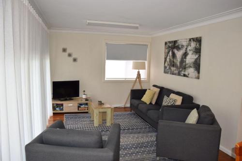 a living room with a couch and a tv at Mariner 16 Flat 1 - Bring your own linen in South West Rocks
